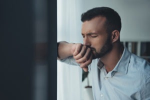 anxiety man up against window eyes closed