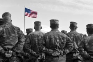 black and white photo of soldiers in front of colored flag