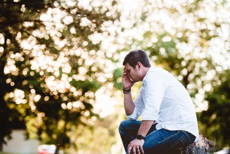 man sitting with hand over face