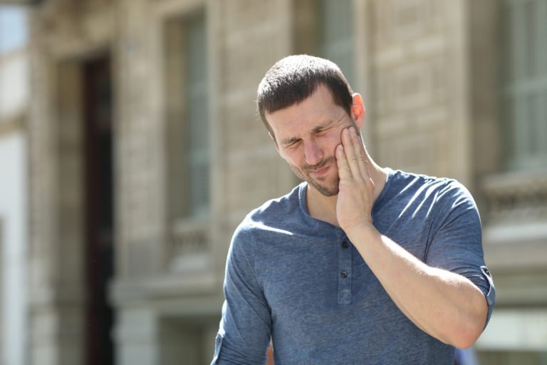 man experiencing jaw and cheek pain due to Temporomandibular joint dysfunction TMJ