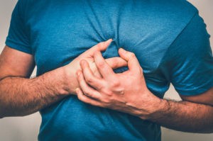 man clutching chest due to chest pain caused by cardiovascular disease