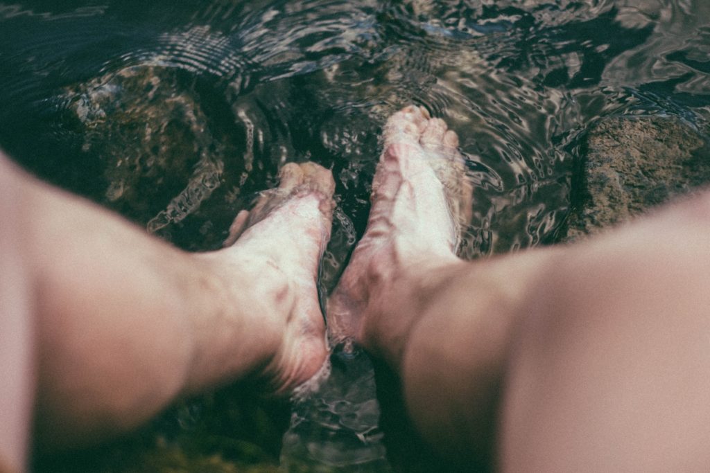 person with legs in water to treat arthritis in ankle