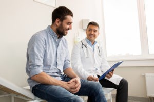 smiling male patient undergoing independent medical exam (ime) with doctor in exam room