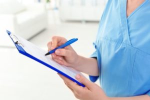 nurse holding and writing on clipboard