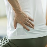 person clutching waist while sitting down caused by hip pain